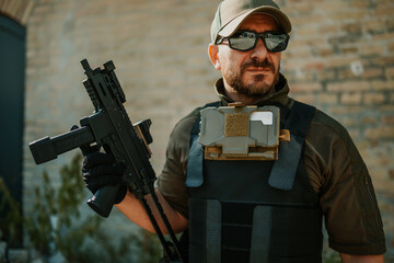 Wall Mural - Soldier holding submachine gun and wearing tactical vest and sunglasses