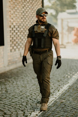 Wall Mural - Soldier walking on cobblestone street wearing tactical gear and sunglasses