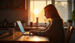 © Jason - A contemplative woman using a laptop at a cozy kitchen table. The warm sunset light creates a serene atmosphere, enhancing the home working experience.