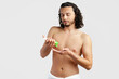 © fotofabrika - A young man applying skincare cream on his face with a focused expression, demonstrating personal grooming at home