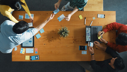Programmer sharing Ux Ui design for mobile phone interface idea with software developer at meeting while designer writing idea at sticky notes. Start up team develop wireframe prototype. Convocation.