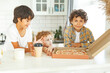 © Olga Gimaeva - Three real happy siblings two brothers and sister eating together pizza at bright scandinavian kitchen