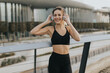 © BGStock72 - A joyful young woman enjoying music while exercising outdoors near a modern urban setting in the late afternoon light