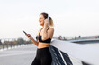 © BGStock72 - A young woman enjoys a peaceful moment listening to music on a tranquil bridge during sunset by the water