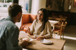 © BGStock72 - A joyful couple enjoys coffee and pastries in a cozy cafe during a sunny afternoon