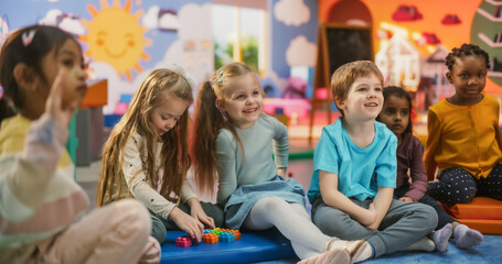 Wall Mural - Cheerful Daycare Teacher Using Gaming and Acting Methods to Teach Multiethnic Kids Alphabet in Kindergarten. Small Cute Boys and Girls Getting Basic Reading and Writing Skills, Learning Alphabet