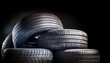 © hardvicore - Pile of used car tires in warehouse area. Industrial waste. Black backdrop.