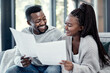 © peopleimages.com - Home, black couple and happy with paperwork on sofa for finance plan or interest rate on loan application. Apartment, people and smile with documents on couch for bank statement and credit score