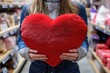 © Popelniushka - A smiling woman choosing a heart-shaped pillow in a colorful store display