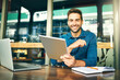 © peopleimages.com - Remote work, happy man and portrait in cafe with tablet, notes and multitask for startup management at laptop. Entrepreneur, smile and tech at table for planning with calendar update in restaurant