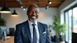 © useful pictures - A confident man wearing a business suit smiles warmly in a stylish office space filled with greenery and natural light, showcasing a professional atmosphere