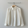 © Jam - A crisp white button-down shirt hangs on a wooden hanger, ready to be worn. It's a simple yet elegant piece of clothing that can be dressed up or down, making it perfect for any occasion