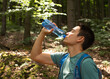 © kieferpix - Young man drinking bottle of water outdoors in nature park