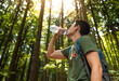 © kieferpix - Active man drinking bottle of water while hiking through the forest