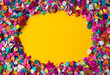 © Favio - Vibrant confetti frame on yellow background for carnival celebrations, with copy space for text.