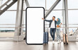 © Prostock-studio - A Muslim couple stands in an airport terminal, holding luggage and a travel document, while pointing at a large blank advertisement board