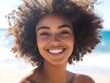 © bvbflo1 - A woman with an afro smiling at the camera on a beach