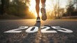 © Thumbs - A runner's foot steps towards the year 2025, painted on the asphalt of a road, as the sun sets behind them