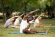 © JackF - African american man practices yoga in a summer park with other athletes of different nationalities