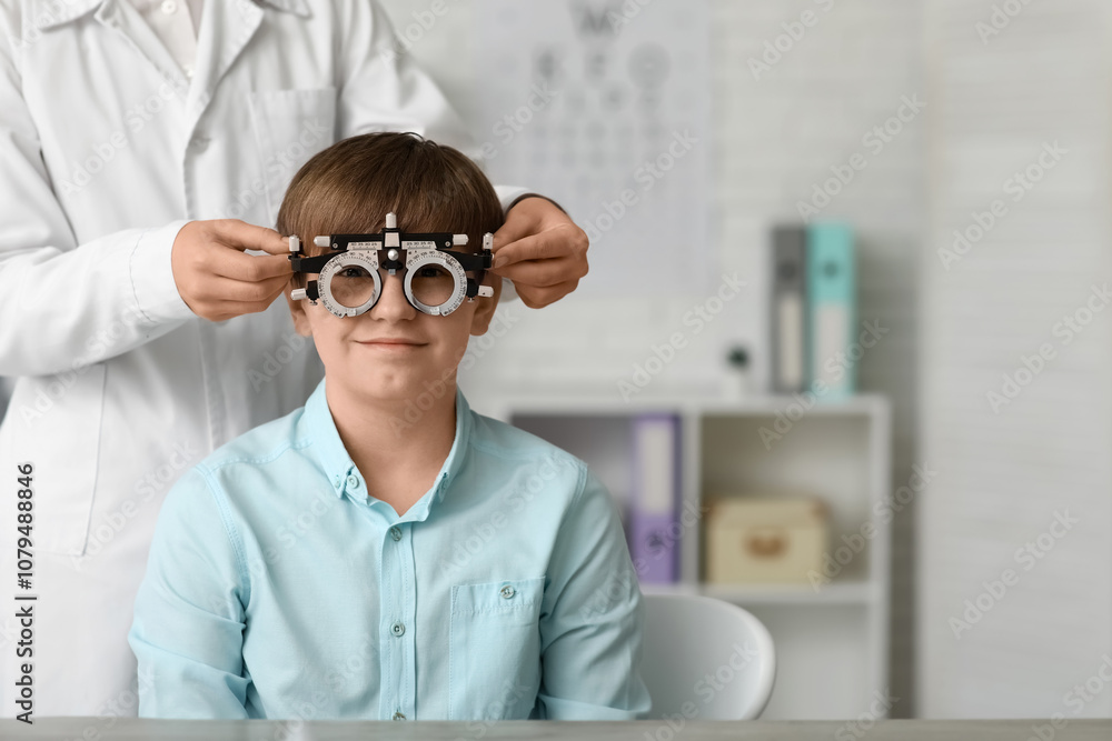 Female ophthalmologist helping little boy undergoing eye test in clinic