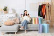 © Pixel-Shot - Happy young woman with mobile phone and credit card sitting on sofa at home. Black Friday sale