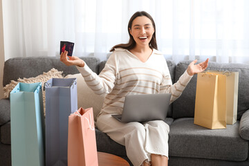 Poster - Young woman with credit card, laptop and shopping bag at home. Black Friday sale