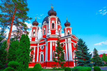 Wall Mural - Curchi Monastery from Moldova. Red and white church stands prominently against a clear blue sky