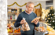 © JackF - Elderly man buyer chooses packaged cookies in christmas decorated grocery store