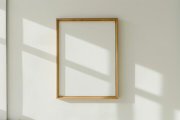 Poster - Empty wooden frame on a white wall with natural sunlight shadows.