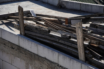 Wall Mural - A pile of construction waste sits on a rooftop.  The pile consists of discarded wood planks, beams, and other building materials. The pile is close to a newly built concrete block wall.