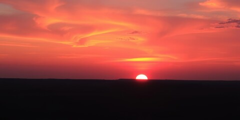 Wall Mural - vibrant hues of orange and pink paint the sky as the sun dips below the horizon, casting a warm glow