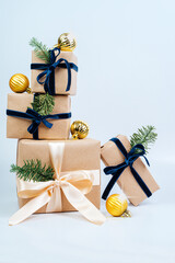 Wall Mural - New Year's gifts in craft paper with a blue bow. Christmas tree with golden balls. Eco style.