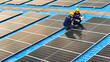© ultramansk - Photovoltaic engineers work on roof top warehouse. workers Inspect and repair the solar panel equipment roof structural. Engineer working set up electrical renewable energy for sustainability.