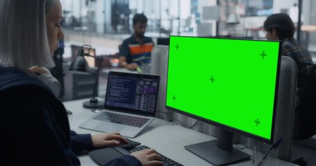 Beautiful Young Caucasian Female Specialist Working on Desktop Computer with Green Screen Mock Up Display. Specialist Working on Software Engineering in a Corporate Office Facility