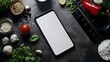 © PSCL RDL - A blank smartphone screen lying on a kitchen counter with cooking ingredients around, for recipe or meal-planning app presentations