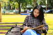 © M Alfan Setyawan - beautiful asian young woman college student focused writing on notebook and reading book in outdoors city park