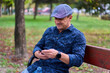 © Xalanx - Mature man using cellphone on a bench in the park