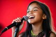 © Gerard - Young girl singing with joy holding microphone against red backdrop