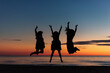 © Cavan Images - Women celebrate friendship by jumping on beach at sunset