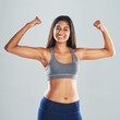 © peopleimages.com - Fitness, portrait and girl flexing arms in studio with smile, confidence and healthy gym champion. Power, muscle and strong Indian woman athlete with happy face, pride or wellness on grey background