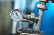 © fotofabrika - A pressure gauge is attached to a metal pipe in a factory setting
