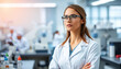 © Sajal.savar - A young Woman in White Coat and Glasses Standing in Medical Science Laboratory Team of Specialists in the Background.