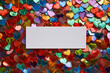 © Марина Веретенникова - An empty white paper rectangle with a place for text in the middle of multicolored sequins in the form of hearts, the concept of Valentine's day.