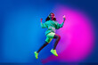 © deagreez - Full length photo of charming positive woman wear sweatshirt headphones jumping winning game device isolated neon blue color background