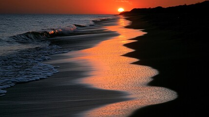 Fototapete - Gentle waves lapping on a quiet sandy beach with a pink and orange sunset reflecting on the water for a serene coastal scene with side empty space for text Stockphoto style