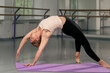 © Guys Who Shoot - in the studio of spiritual development master class on yoga a young girl in bright room on a purple mat does stretching for the back pose asana