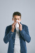 © peopleimages.com - Man, tissue and blowing nose in studio for sneeze, allergies or sick with mucus by white background. Person, paper and cleaning for hygiene, flu or sinusitis with hayfever, eyes closed and healthcare