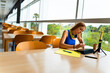 © Alfonso Soler - Pretty college girl studying in the library. Taking notes and using headphones, tablet and phone.
