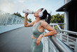 © peopleimages.com - Woman, headphones and drinking water outdoor for fitness, exercise and health with bottle and workout. Athlete, music and challenge in city for training, streaming and drink with healthy cardio run