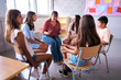 © CarlosBarquero - Diverse happy group of primary school children students sitting on chairs in circle interacting during lesson. Pre-adolescents kids talking together to classmates and female teacher in support class